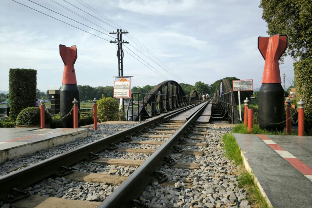 ภาพนี้แสดงสะพานรถไฟที่มีรูปแบบเป็นโครงสร้างเหล็ก และมีรางรถไฟขนาดใหญ่ขยาวขนานไปไกล มีลักษณะเฉพาะอย่างยิ่งจากอุปกรณ์ติดข้างที่มีลักษณะคล้ายกับลูกระเบิดสีดำและสีแดง และมีป้ายข้อความอยู่ด้วย เหมือนกับกลยุทธ์การตลาดบน Line OA เพื่อเพิ่มยอดขาย ควรสร้างเอกลักษณะและสิ่งที่ดึงดูดสำหรับผู้ใช้ Line OA เช่นการสร้างคอนเทนต์ที่น่าสนใจและมีประโยชน์ เพื่อทำให้ผู้ใช้สนใจและมีอุปสรรคในการซื้อสินค้า เช่นเดียวกับสะพานรถไฟที่น่าสนใจและมีความเป็นเอกลักษณะของตัวเอง